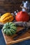 Vertical shot of multi-colored pumpkins lying on a straw sack and on a wooden board