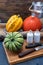 Vertical shot of multi-colored pumpkins lying on a straw sack and on a wooden board