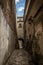 Vertical shot of a narrow alley of aged buildings under a blue sky at daytime