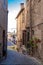 Vertical shot of a narrow paved street passing through old medieval residential buildings in Italy