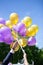 Vertical shot of newlywed couples holding yellow and purple helium balloons in the sky