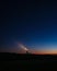 Vertical shot of the night over the silhouette of the land and a lighthouse in the background