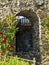 Vertical shot of an old building with an arched entrance covered in red roses on a sunny day