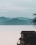 Vertical shot of an old cottage by a lake with the hills in the background