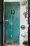 Vertical shot of an old green wooden door with a padlock, wreath and white metal candle holder