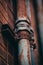 Vertical shot of old and rustic metal pipes on brick-walled building