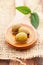 Vertical shot of olives on a wooden spoon with a leaf of basil