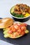 Vertical shot of open bagel with avocados and tomatoes near a meat bowl