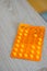 Vertical shot of an orange pile of medical tablets on a wooden surface