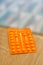 Vertical shot of an orange pile of medical tablets on a wooden surface