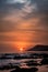 Vertical shot of an orange sunset with silhouette of hills on the beach