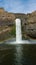 Vertical shot of the Palouse Falls with the rainbow over it in the United States