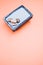 Vertical shot of pebbles on a rectangular box filled with small blue rocks on pink background