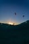 Vertical shot of people flying parachutes under the breathtaking sunset over the ocean