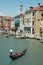 Vertical shot of people riding gondolas on the body of water near buildings in Venice, Italy