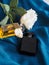 Vertical shot of perfumes bottles and white roses on a blue fabric surface