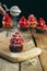 Vertical shot of a person adding sugar powder on a cupcake with red cream through a strainer