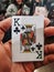 Vertical shot of a person holding a king of clubs playing card with a blurred background