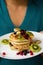 Vertical shot of a person holding a plate with pancakes with fruits