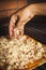 Vertical shot of a person pouring cheese on a homemade pizza on an oven