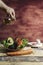 Vertical shot of a person pouring oil into the salad with fresh tomatoes and avocado