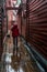 Vertical shot of a person in a raincoat walking in a narrow alley in the Bergen old town, Norway