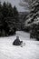 Vertical shot of a person sitting on the hill wearing snowboard