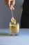 Vertical shot of a person stirring coffee with a spoon in a transparent cup on a white surface