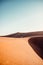 Vertical shot of a person walking among the magnificent sand dunes in the desert