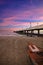 Vertical shot of a pier with stone walls and lampposts at the beach with a purple sky at sunset