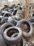 Vertical shot of a pile of old used automotive tires littering natural landscape. Pollution concept.