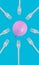 Vertical shot of a pink balloon with disposable plastic forks on a blue background