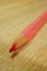 Vertical shot of a pink drawing pencil on a wooden surface