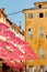 Vertical shot of pink umbrellas hanging above a street of a Grasse in France