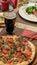 Vertical shot of a pizza next to a glass of coke and another dish