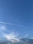 Vertical shot of plane tracks on a blue sky during a sunny day