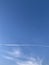 Vertical shot of plane tracks on a blue sky during a sunny day