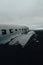 Vertical shot of the plane wreck at Solheimasandur in a gloomy field in Iceland under a stormy sky