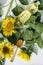 Vertical shot. Plastic bottle of sunflower oil and wooden spoon of oil on the green leaves, blooming sunflowers, top view