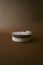 Vertical shot of a plastic bowl of creamy white pudding on a brown surface