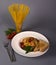 Vertical shot of a plate with cooked pasta with a glass of raw pasta