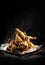 Vertical shot of a plate of a delicious fried chicken on a black background