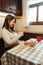 Vertical shot of pregnant Latina woman using cell phone while eating breakfast