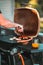 Vertical shot of the process of sausage barbeque, person picking a sausage with a tong picker