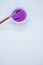 Vertical shot of purple watercolor paint on a bowl and paintbrush isolated on yellow background