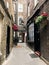 Vertical shot of a quiet narrow alleyway leading to the brick building with an arch, London