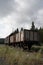 Vertical shot of railway carriages in the field under the dark cloudy sky
