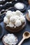 Vertical shot of raw raffaello in a wooden bowl with coconut chunks and a wooden spoon