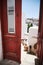 Vertical shot of a red door leading to a balcony with a beautiful view of Amorgos, Greece