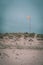 Vertical shot of a red flag raised on a cross shaped pole on top of a hill on a sandy beach